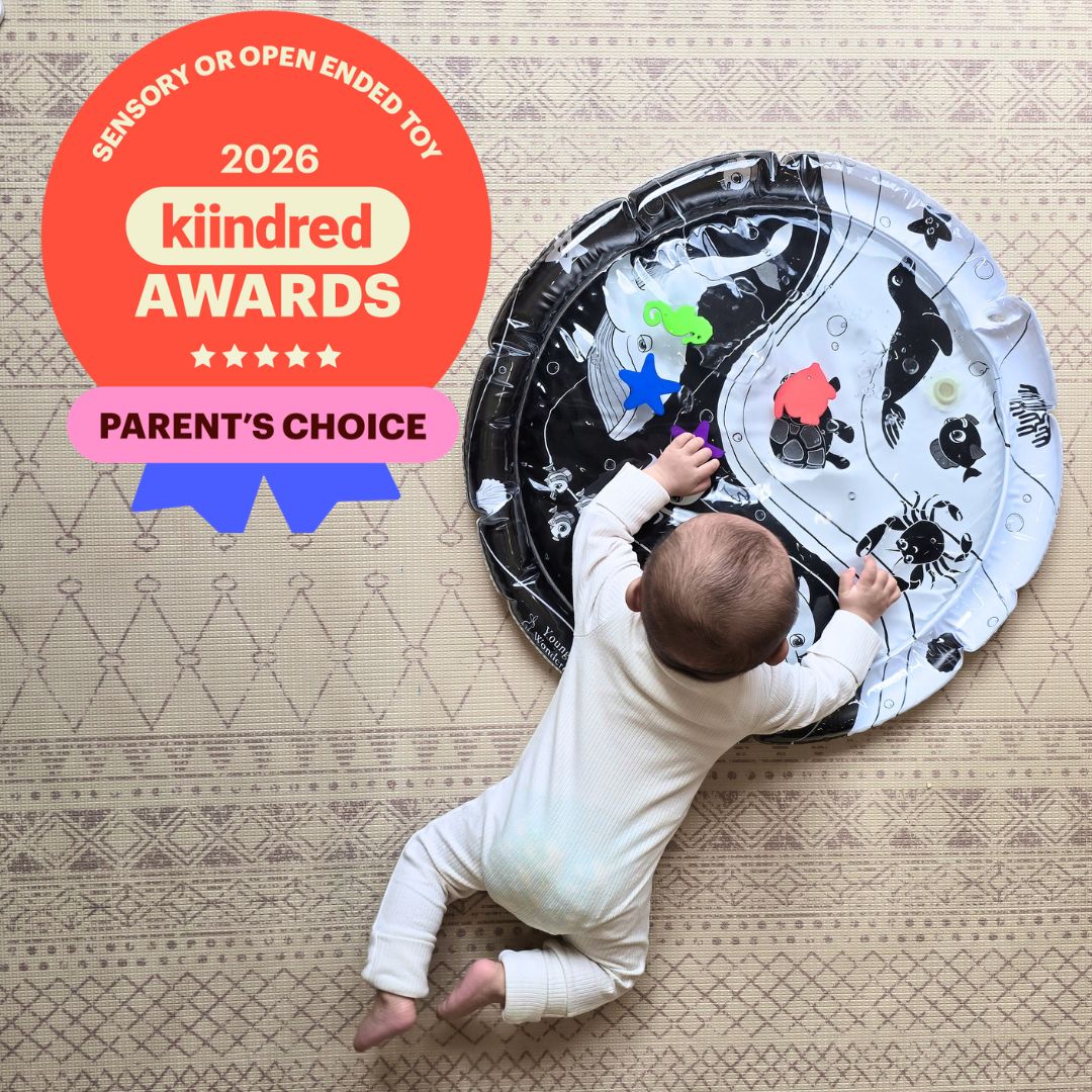 Baby reaching for colourful sea creatures on Young Wonderer's black and white Under the Sea Sensory Water Mat, 2026 Kiindred Parents' Choice Award winner